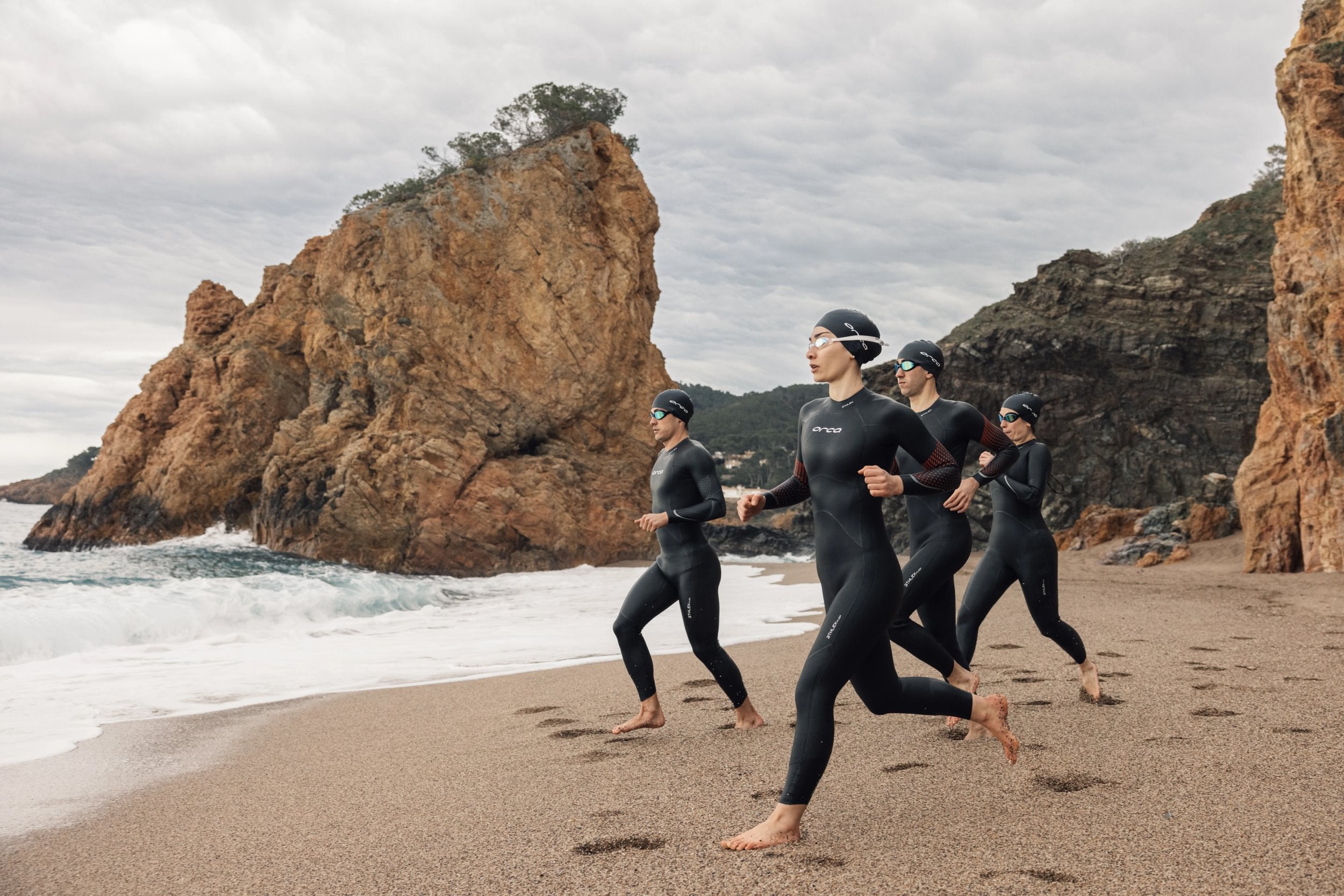 Group running towards water in Orca Wetsuits